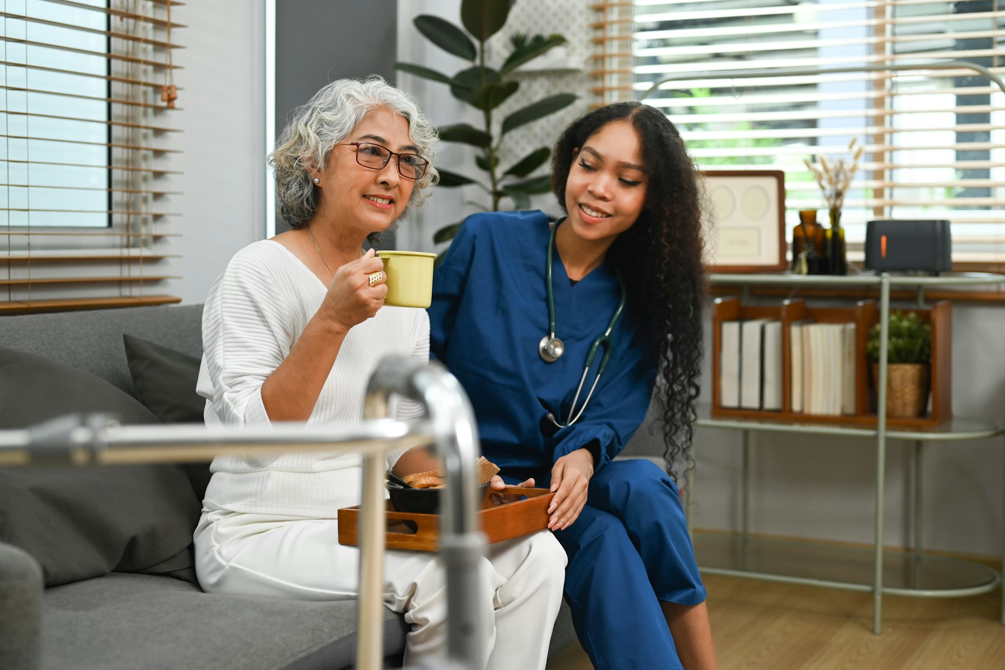 Image of caring female doctor taking care of elderly woman during home care visit.