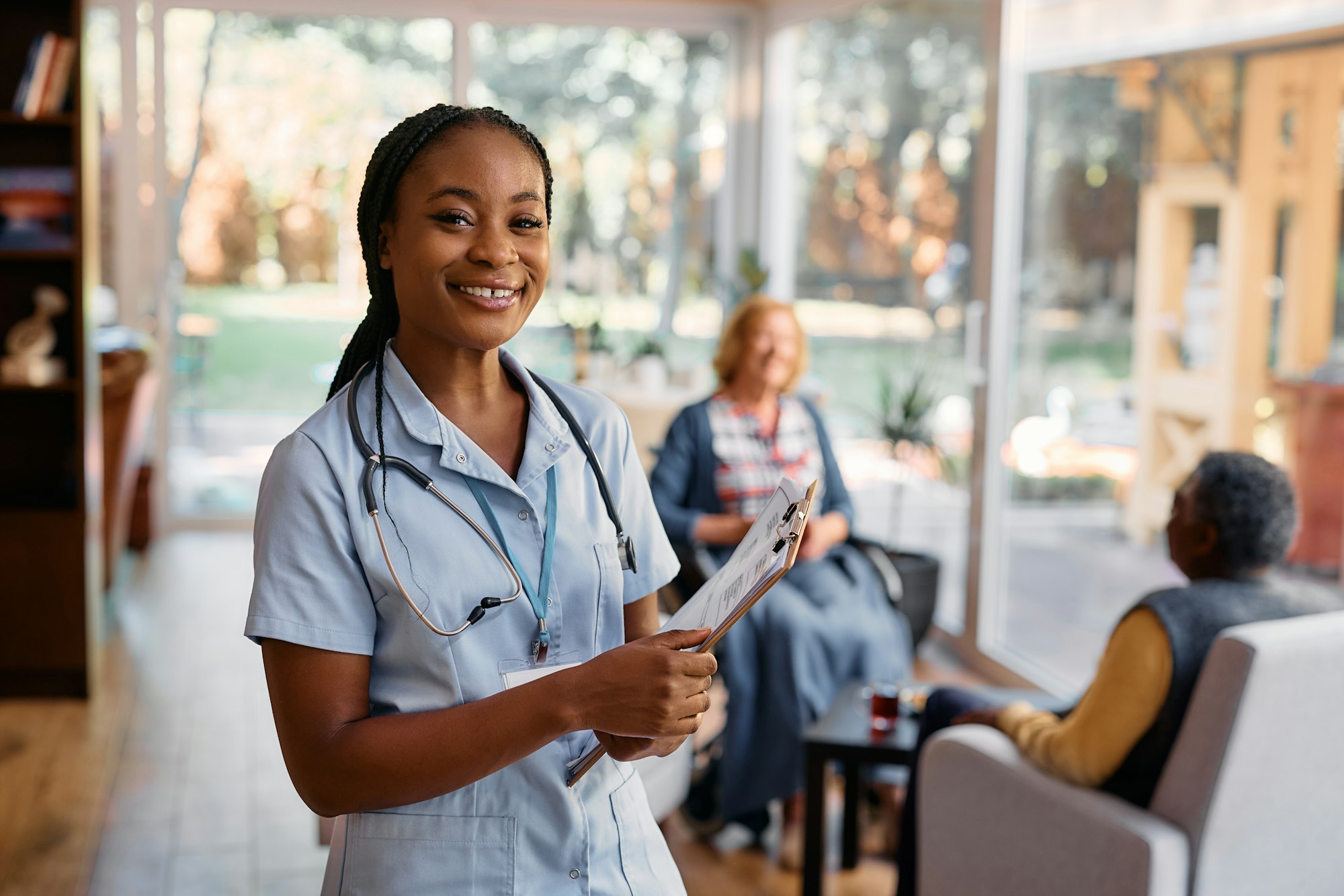 Young happy black nurse working at residential care home and looking at camera.